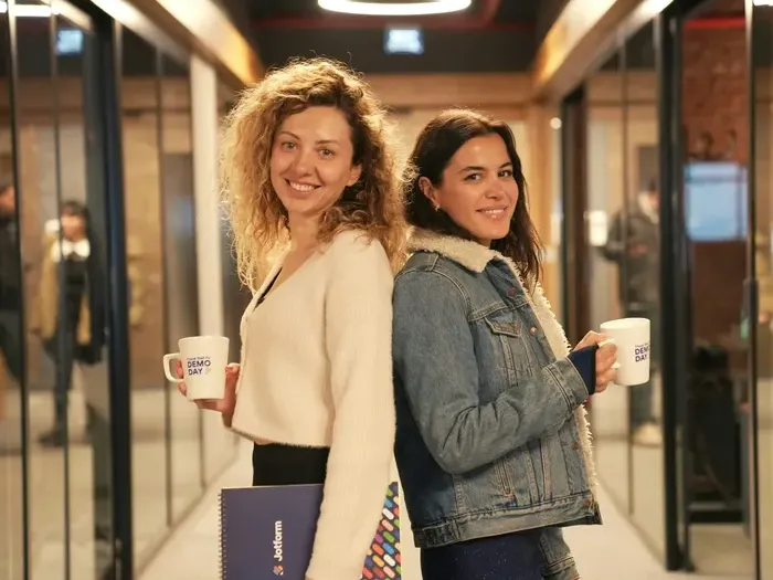 Two smiling colleagues with coffee mugs in a modern corridor, representing local businesses on Local Biz Link